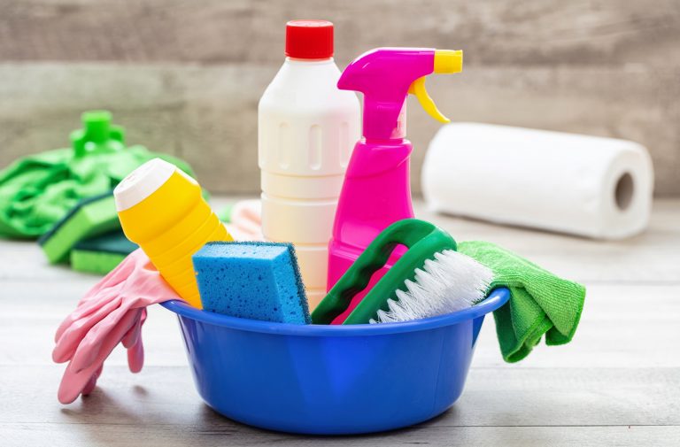 Cleaning supplies in a blue bowl, wooden floor background.